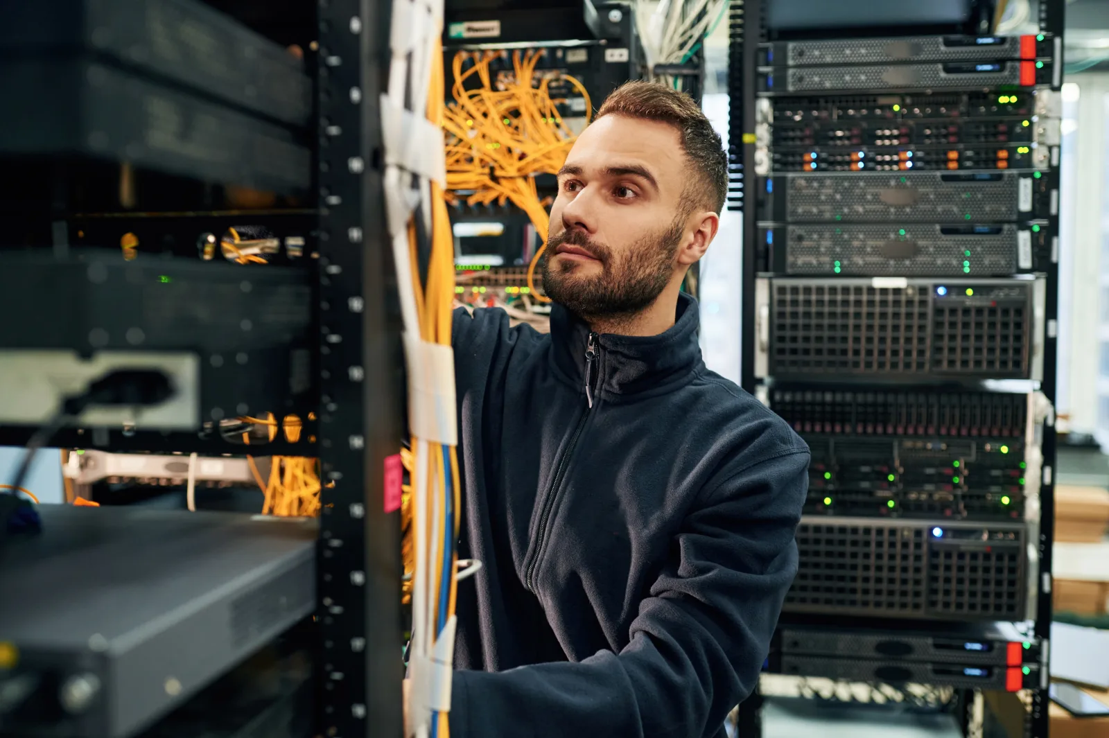 Un sistemista lavora sui cavi di rete dentro un armadio rack pieno di server